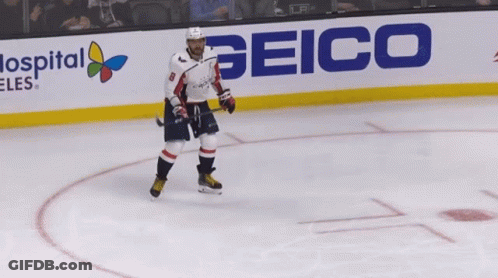 A Hockey Player Is Standing On The Ice In Front Of A Sign For Geico GIF