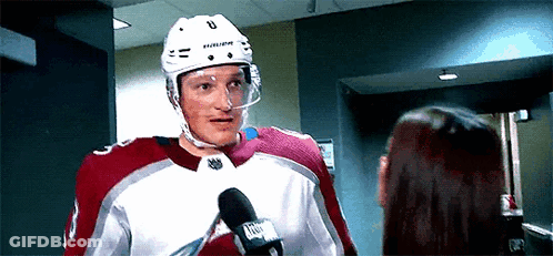 A Hockey Player Is Talking Into A Microphone While Standing Next To A Woman . GIF