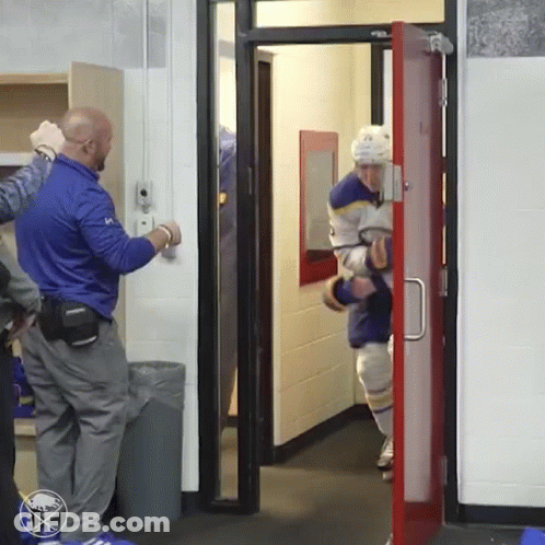 A Hockey Player Is Walking Through A Door With A Sabres Logo On The Wall Behind Him GIF