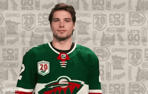 A Hockey Player Is Wearing A Green Jersey With The Number 20 On It GIF