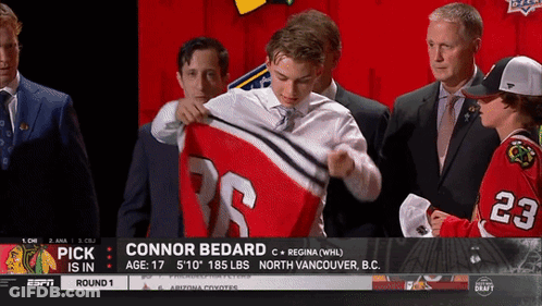 A Hockey Player Named Connor Bedard Is Being Presented With His Jersey GIF
