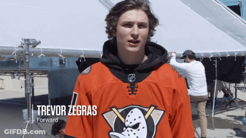 A Hockey Player Named Trevor Zegras Stands In Front Of A White Tent GIF