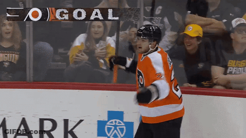 A Hockey Player Stands On The Ice In Front Of A Banner That Says Goal GIF