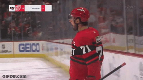 A Hockey Player Stands On The Ice With A Geico Sign In The Background GIF
