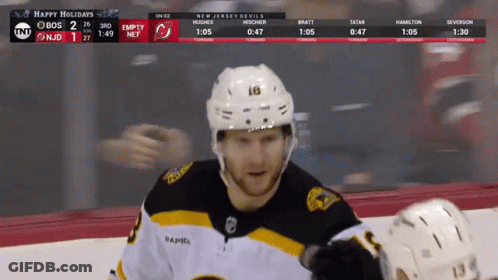 A Hockey Player Stands On The Ice With A Scoreboard Behind Him That Says Happy Holidays GIF