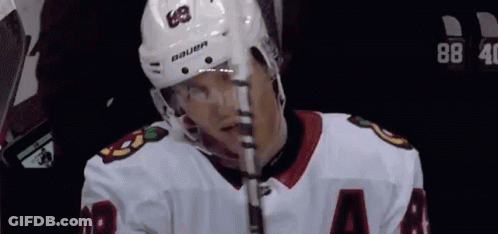 A Hockey Player Wearing A Bauer Helmet Is Holding A Hockey Stick GIF