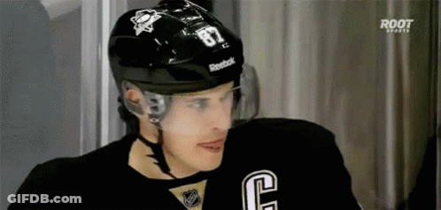 A Hockey Player Wearing A Black Helmet And A Black Jersey With The Number 87 On It . GIF