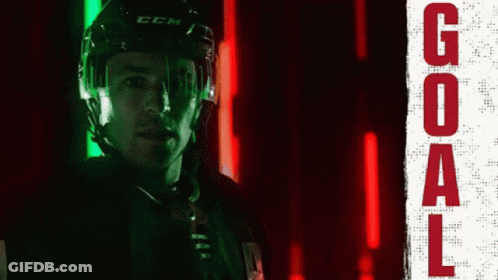 A Hockey Player Wearing A Ccm Helmet Stands In Front Of A Neon Sign That Says Goal GIF