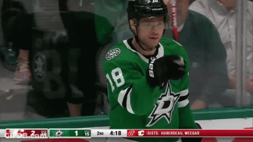 A Hockey Player Wearing A Green Number 18 Jersey GIF