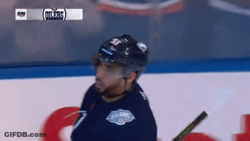 A Hockey Player Wearing A Helmet And A Jersey That Says Oilers On It GIF