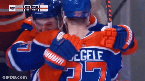 A Hockey Player Wearing A Number 25 Jersey Is Hugging Another Player GIF