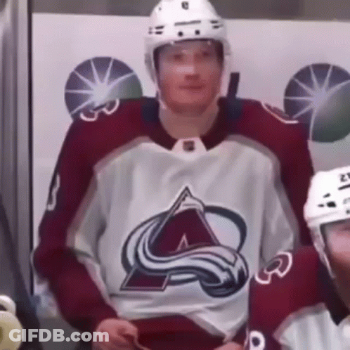 A Hockey Player Wearing A Red And White Jersey And A Helmet Is Sitting In The Stands . GIF