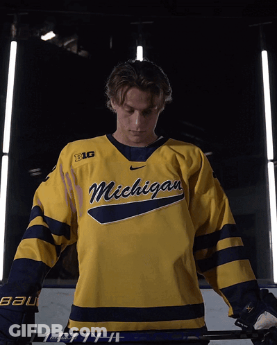 A Hockey Player Wearing A Yellow Michigan Jersey GIF