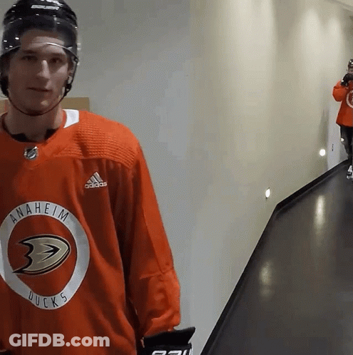 A Hockey Player Wearing An Anaheim Ducks Jersey Stands In A Hallway GIF