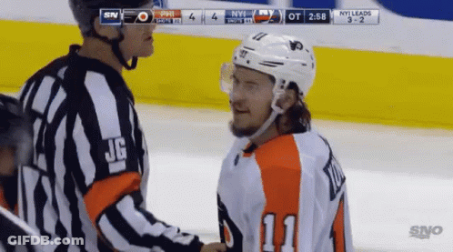 A Hockey Player Wearing Number 11 Shakes Hands With A Referee During A Game GIF