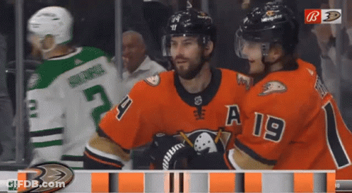 A Hockey Player With A 19 On His Jersey Stands Next To Another Player GIF