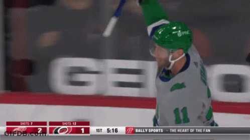 A Hockey Player With The Number 11 On His Jersey Is Holding A Stick In The Air GIF