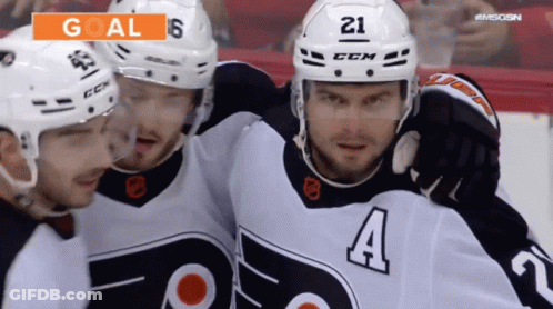 A Hockey Player With The Number 21 On His Helmet Is Surrounded By His Teammates GIF