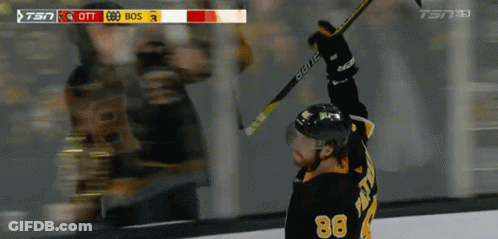 A Hockey Player With The Number 88 On His Jersey Holds His Stick In The Air GIF