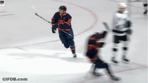 A Hockey Player With The Number 9 On His Jersey Is Holding A Stick GIF