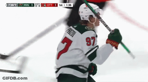 A Hockey Player With The Number 97 On His Jersey Is Holding A Hockey Stick . GIF