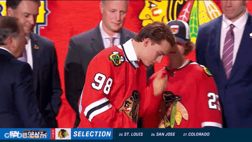 A Hockey Player With The Number 98 On His Jersey Stands Next To Another Player GIF