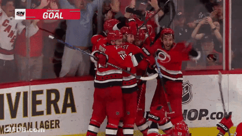 A Hockey Team Celebrates A Goal In Front Of A Riviera Advertisement GIF