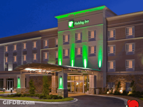 A Holiday Inn Hotel With Green Lights On The Front Of It GIF