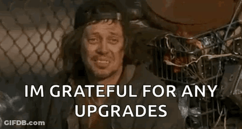 A Homeless Man Is Smiling And Saying `` Im Grateful For Any Upgrades '' While Sitting Next To A Trash Can . GIF
