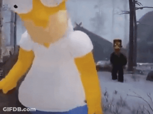 A Homer Simpson Mascot Is Standing In The Snow In Front Of A House GIF
