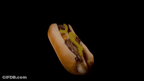 A Hot Dog On A Bun With Mustard And Pickles GIF