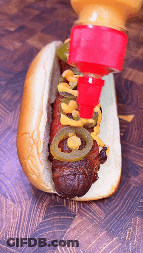 A Hot Dog With Jalapenos And Mustard Is Being Poured On It GIF