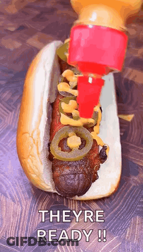 A Hot Dog With Mustard And Jalapenos Is Being Poured On It GIF