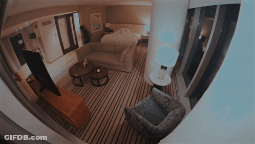 A Hotel Room With A Couch A Chair And A Tv GIF