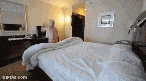 A Hotel Room With A Large Bed And A Basketball Hoop On The Wall GIF