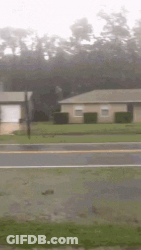 A House Is Sitting On The Side Of The Road Next To A Street . GIF