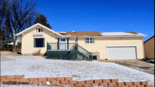 A House With Snow On The Ground And A Flag On The Porch GIF