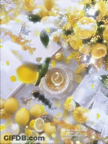 A Hummingbird Is Flying Over A Cup Of Tea Surrounded By Lemons And Flowers GIF