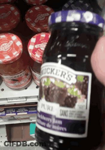 A Jar Of Mucker 'S Blackberry Jam Is Being Held Up GIF