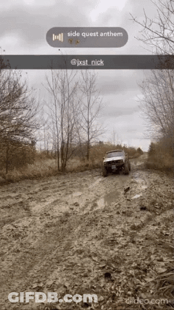 A Jeep Is Driving Down A Muddy Road With Trees In The Background GIF