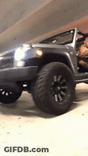 A Jeep Is Parked In A Garage With The Doors Open GIF