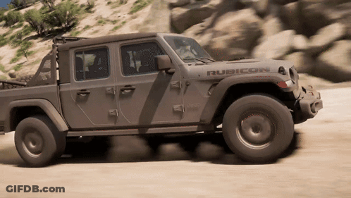 A Jeep Rubicon Is Driving Down A Sandy Road GIF