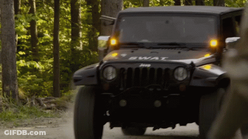A Jeep With The Word Swat On The Front Is Driving Down A Dirt Road GIF