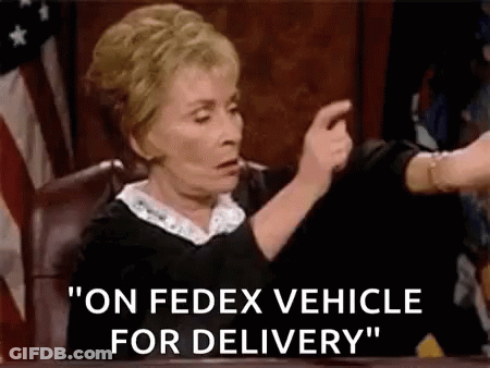 A Judge Is Pointing At A Fedex Vehicle For Delivery While Sitting At A Desk . GIF