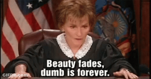 A Judge Is Sitting At A Desk In Front Of An American Flag And Says `` Beauty Fades , Dumb Is Forever '' . GIF