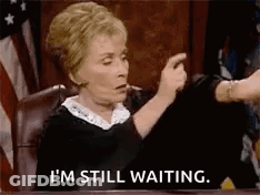 A Judge Is Sitting At A Table In A Courtroom And Says `` I 'M Still Waiting '' . GIF