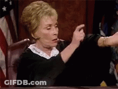 A Judge Is Sitting At A Table In A Courtroom Pointing At Something . GIF