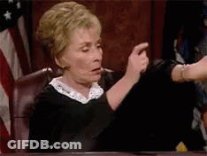 A Judge Is Sitting At A Table In A Courtroom Pointing At Something . GIF