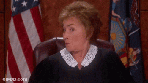 A Judge Is Sitting In A Courtroom With Her Hands Outstretched . GIF