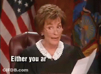 A Judge Is Sitting In Front Of An American Flag And Holding A Piece Of Paper In Her Hand . GIF
